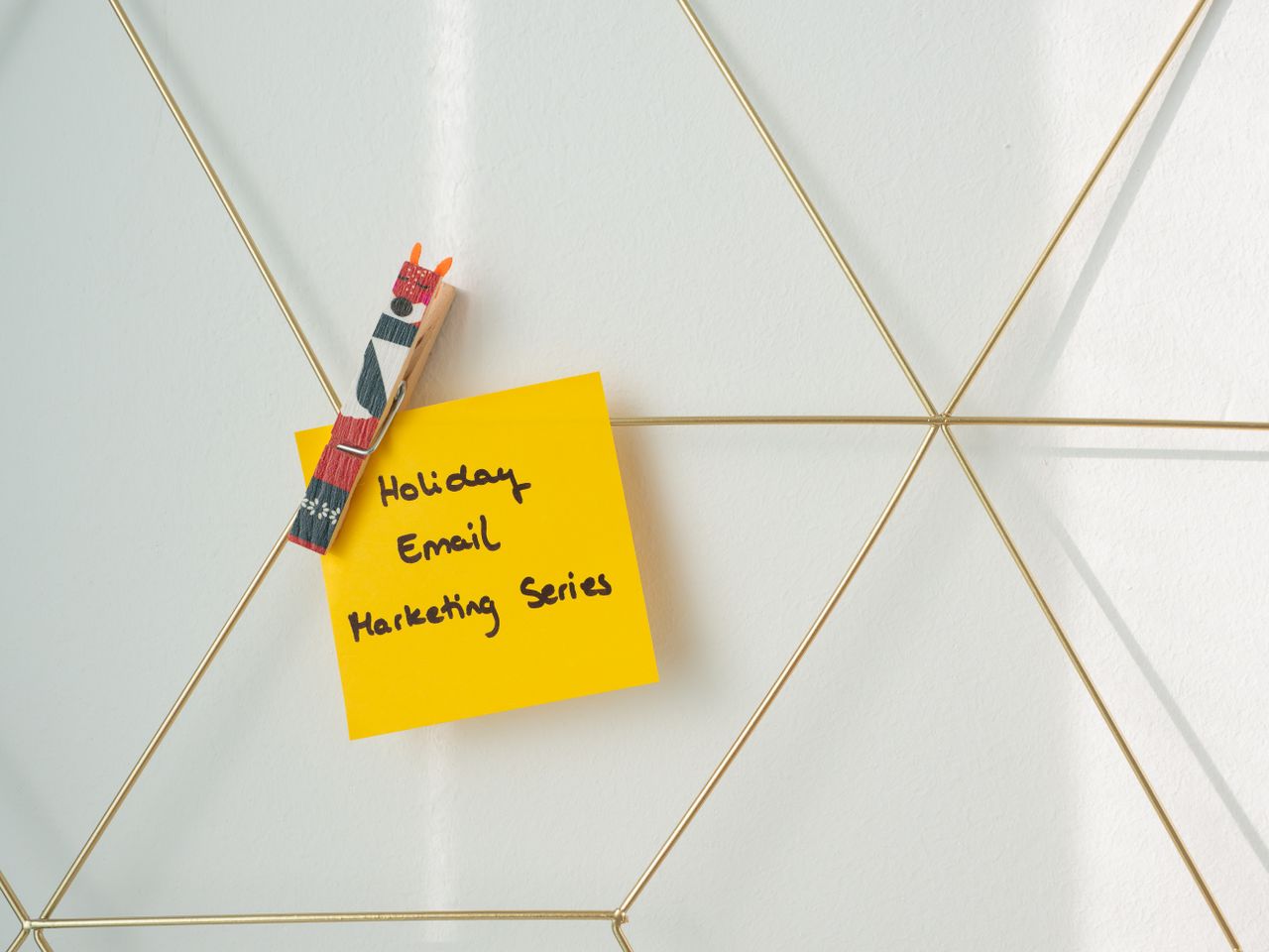 heros-img Bright yellow sticky note with holiday email marketing message clipped to a wireframe wall.